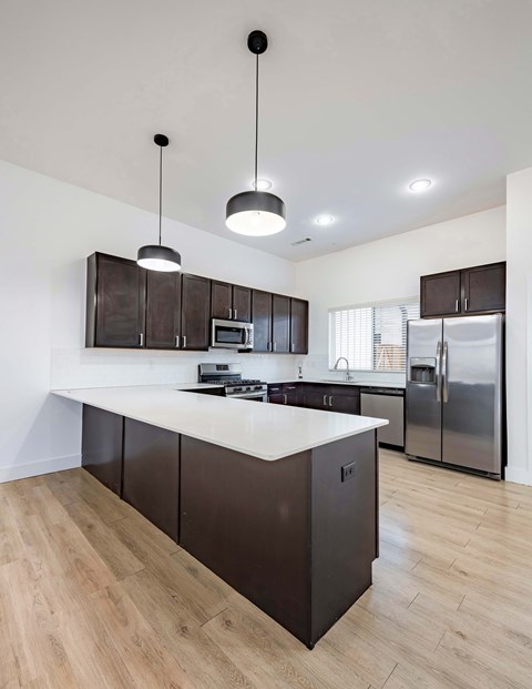 A modern kitchen with dark brown cabinets and a white countertop.